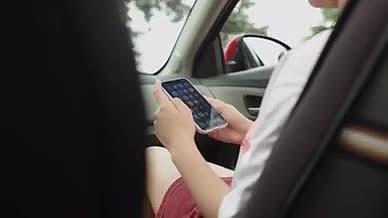 时尚靓丽的年轻女士在车内使用新款智能手机视频的预览图